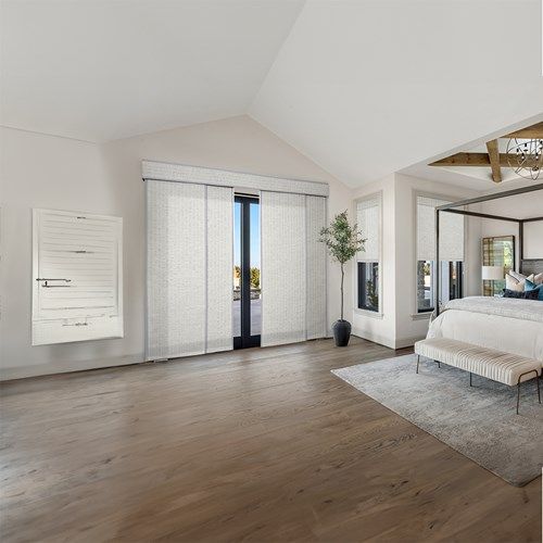 a large bedroom with white walls and wood flooring, along with a bed in the middle