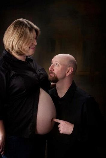 a man and woman standing next to each other in front of a dark background,