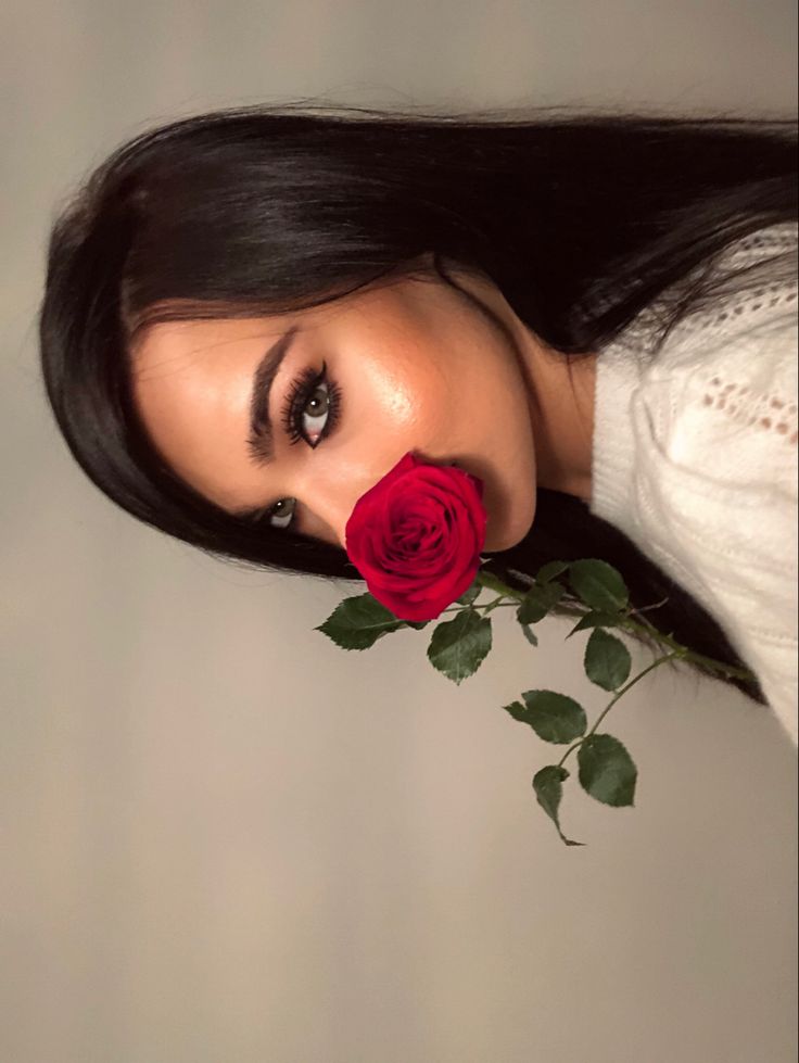 a woman with long black hair holding a red rose