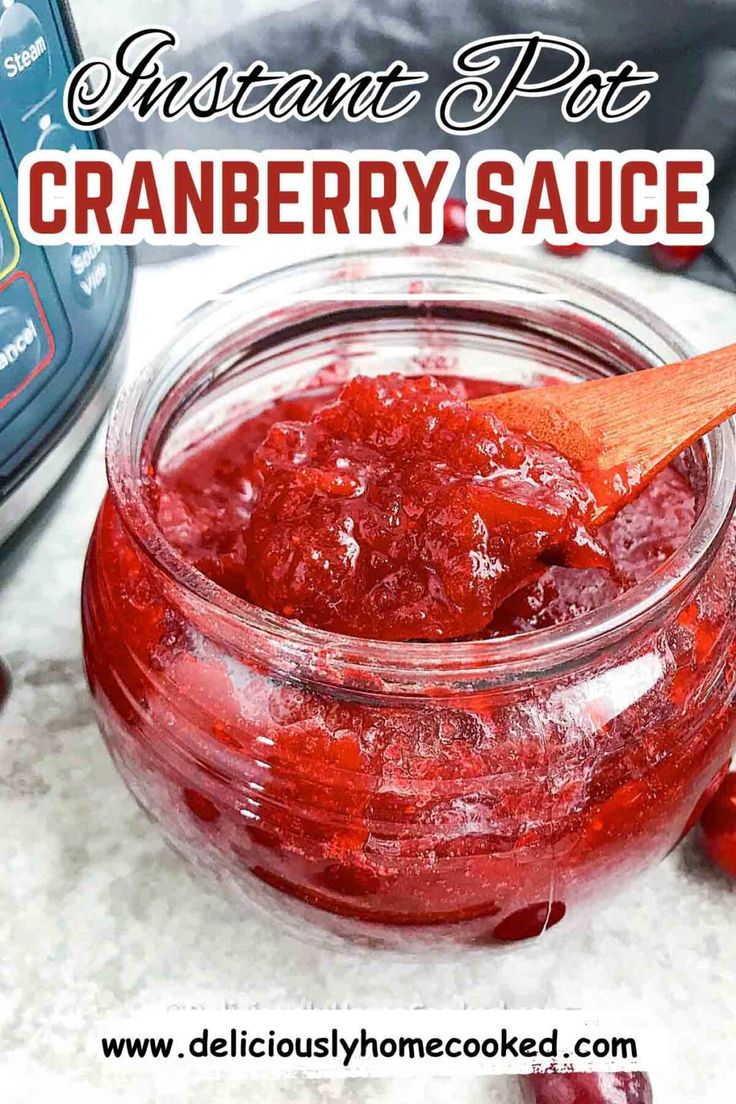 cranberry sauce in a glass jar with a wooden spoon next to it on a table