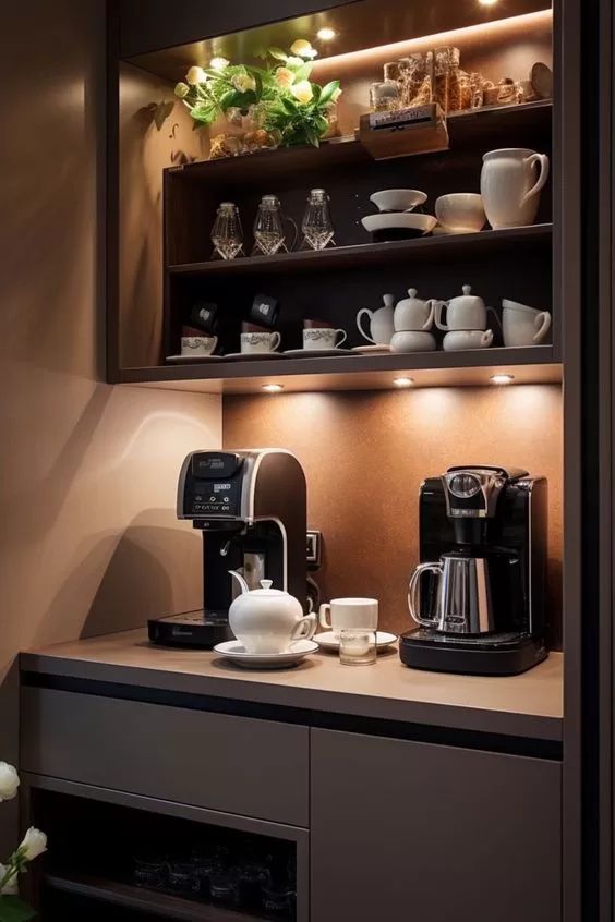 a coffee maker and some cups on a counter in a room with lights above it