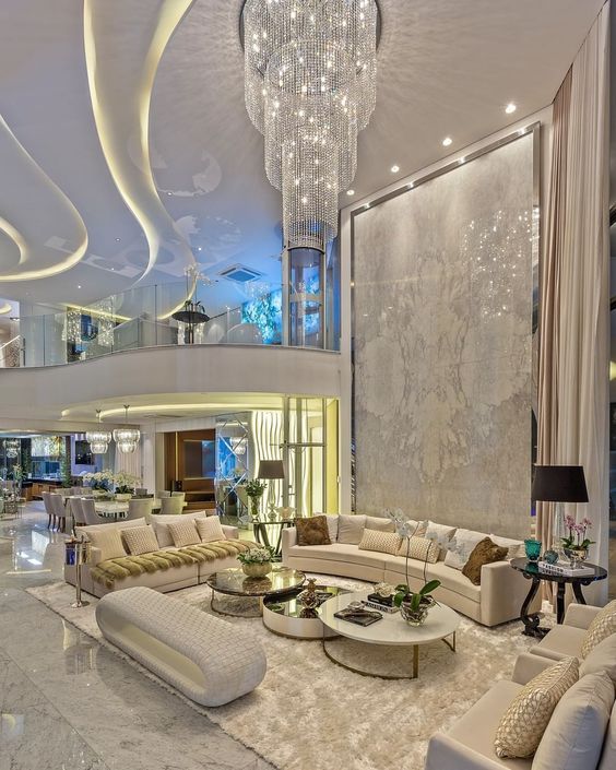 a living room filled with lots of furniture and a chandelier hanging from the ceiling