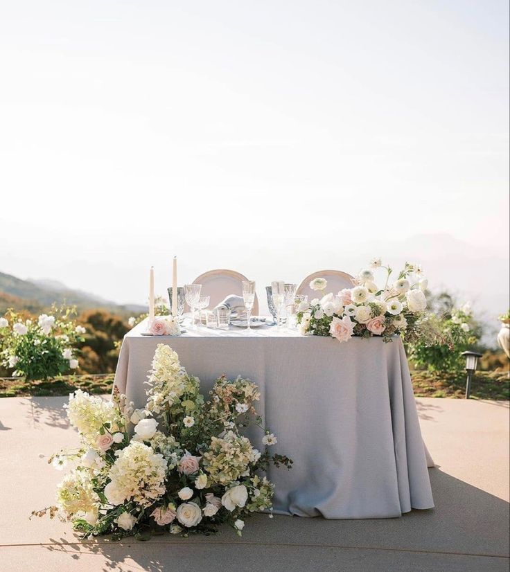 the table is set with flowers and candles for an outdoor wedding reception in the mountains