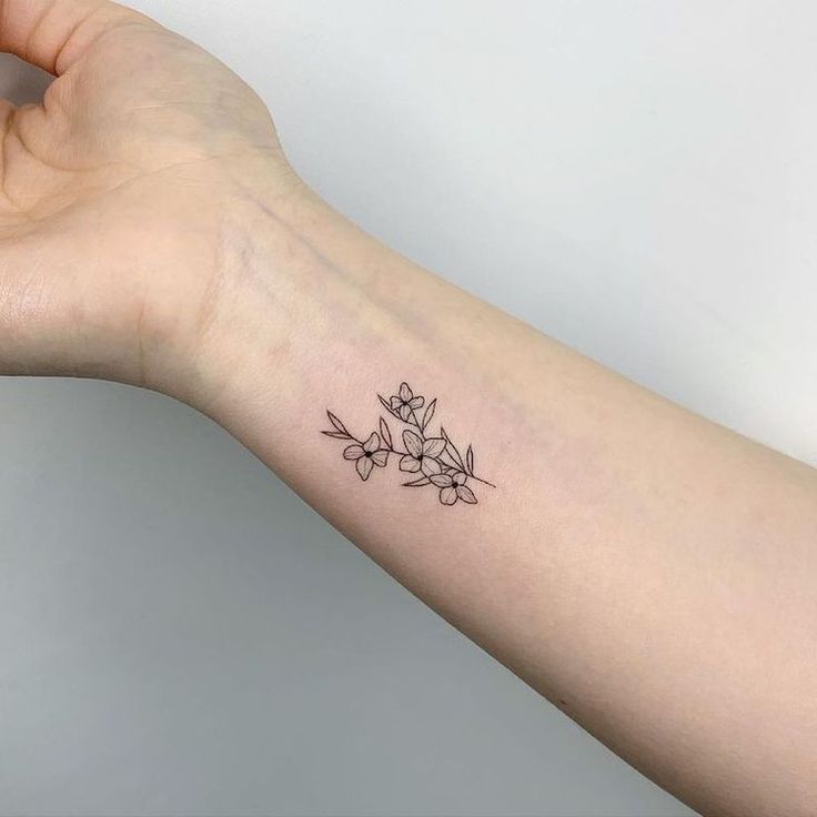 a woman's arm with a small flower tattoo on it