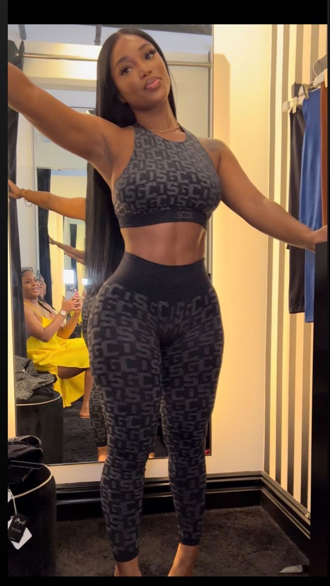 a woman standing in front of a mirror wearing leggings and sports bra top