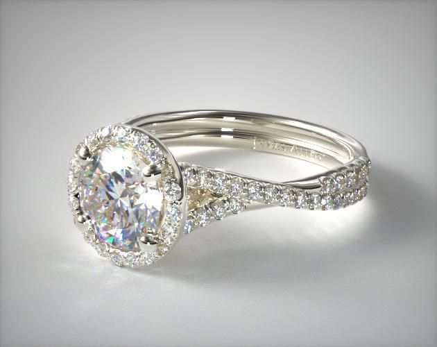 a white gold ring with an oval cut diamond surrounded by pave - set diamonds