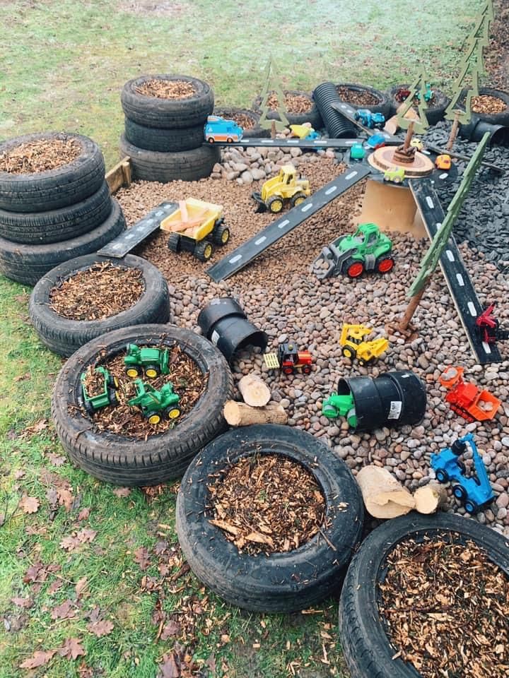 a pile of tires sitting on top of a grass covered field next to toy cars