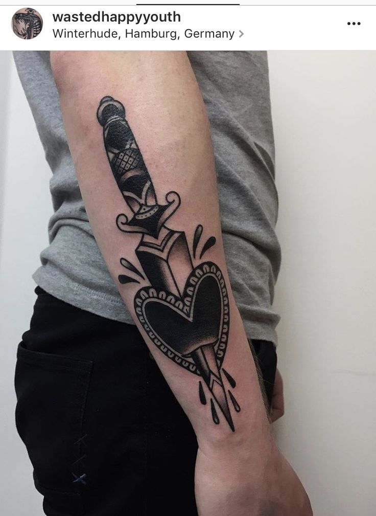 a man with a tattoo on his arm holding a knife in the shape of a heart