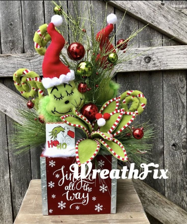 a christmas arrangement in a red box with candy canes and grin - face decorations