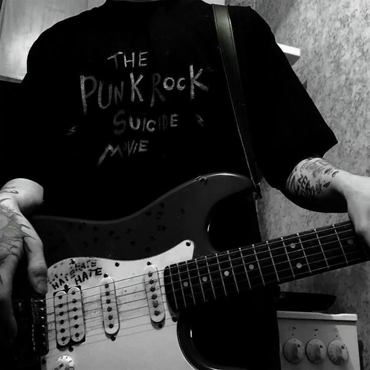 a man with tattoos playing an electric guitar