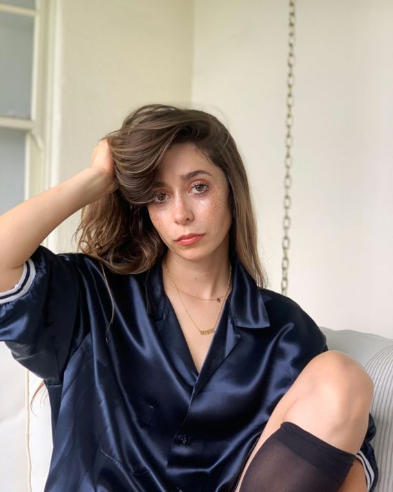 a woman sitting on a couch with her hair in the air and wearing sheer stockings