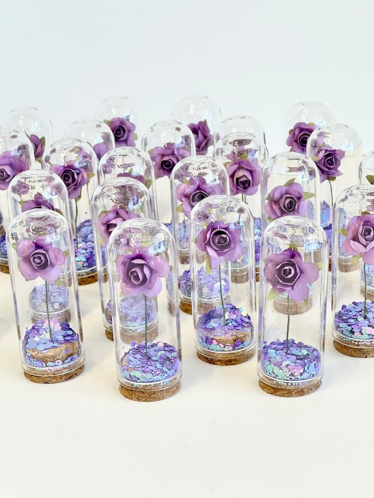 several glass vases with purple flowers in them