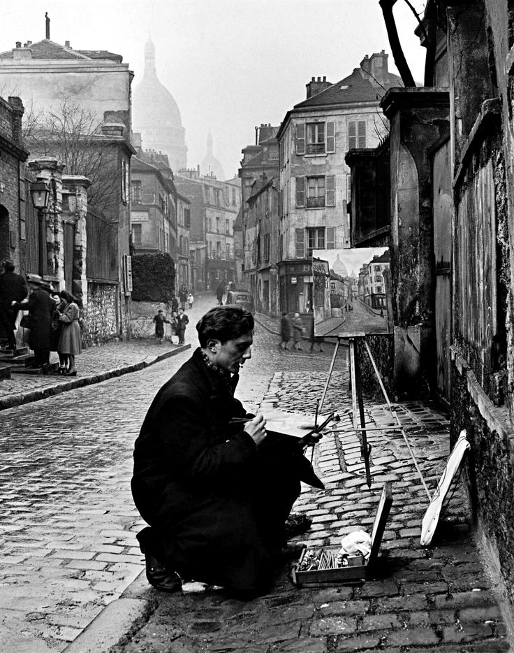 an old black and white photo of a woman sitting on the ground with her painting