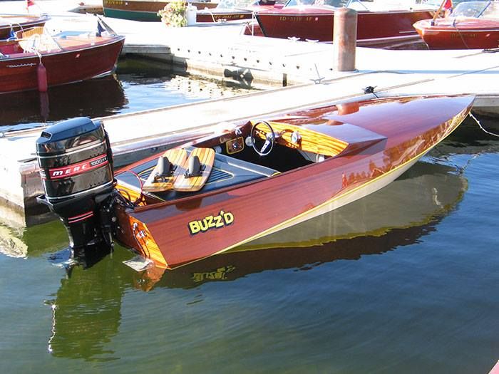 a red and yellow speed boat parked in the water at a dock with other boats