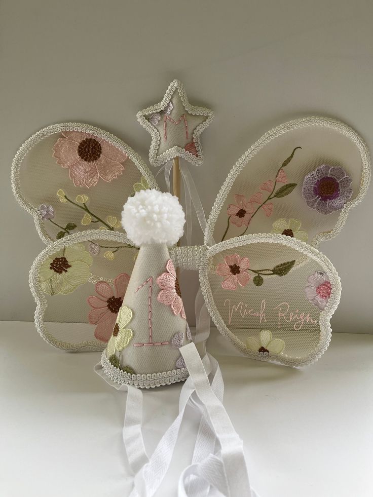 a white table topped with a butterfly shaped cake topper and two napkins next to it