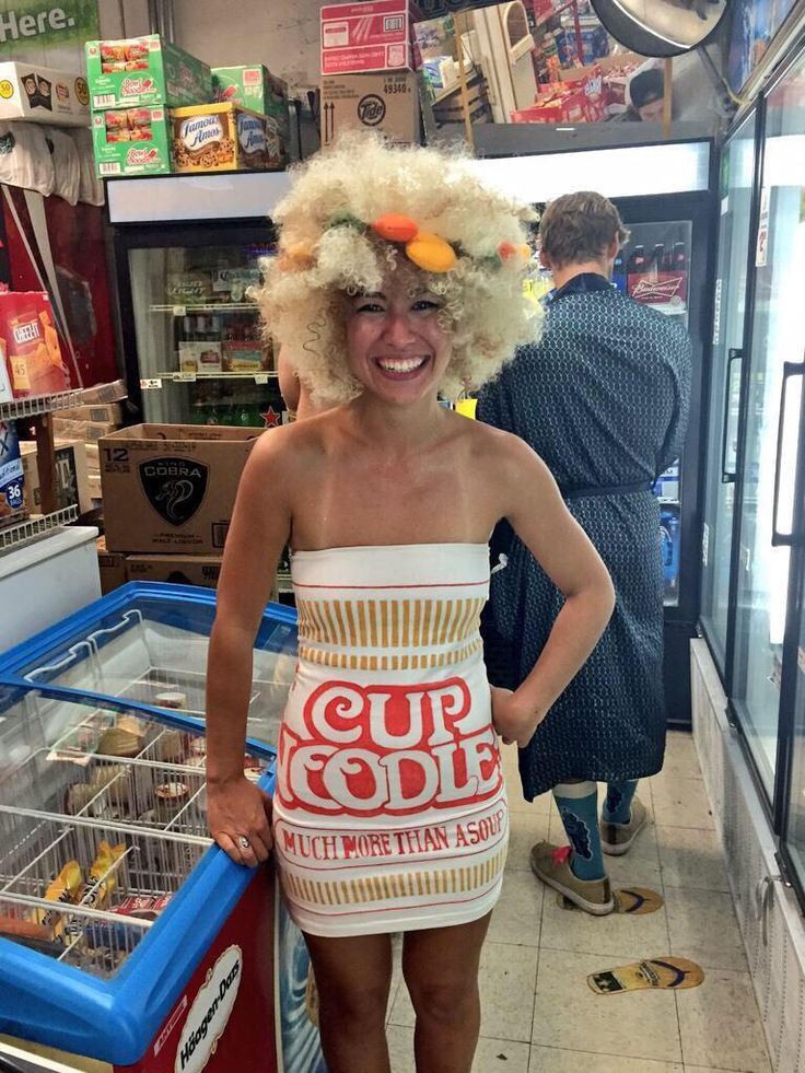 a woman in a wig and dress standing next to a vending machine