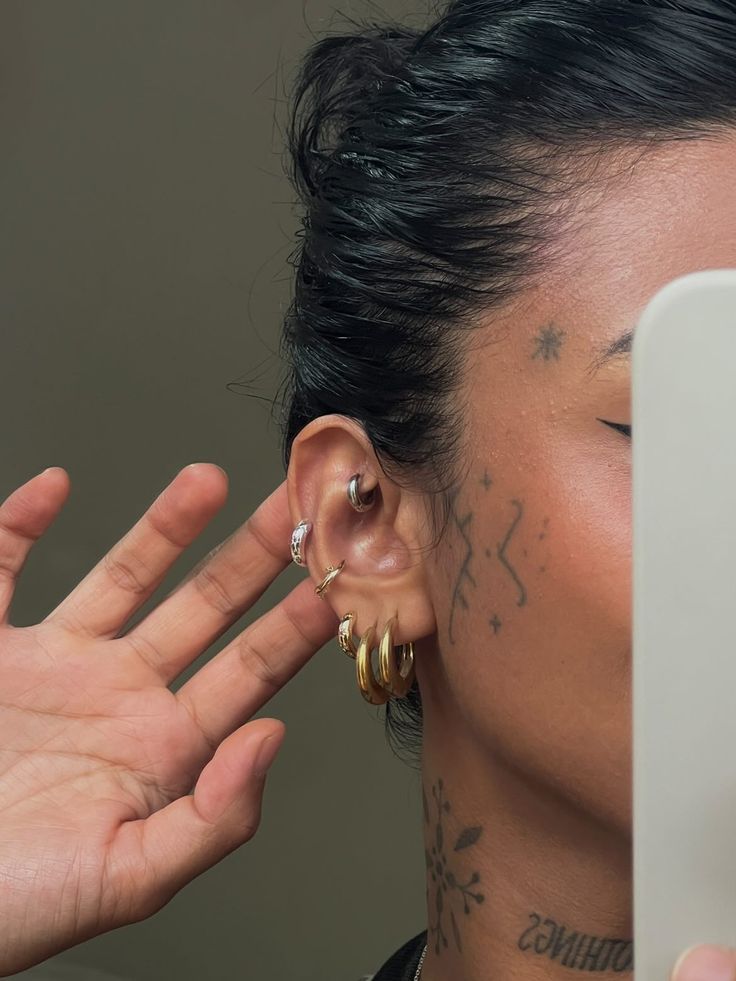 a close up of a person with tattoos on their face and behind them is a pair of ear piercings