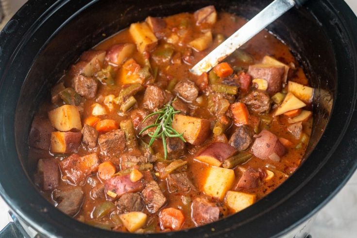 a close up of a pot of stew with meat and vegetables in the slow cooker