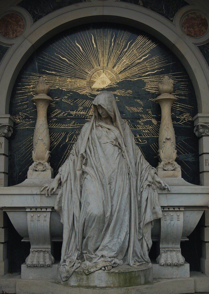 the statue is standing in front of an ornate doorway with columns and a sunburst above it