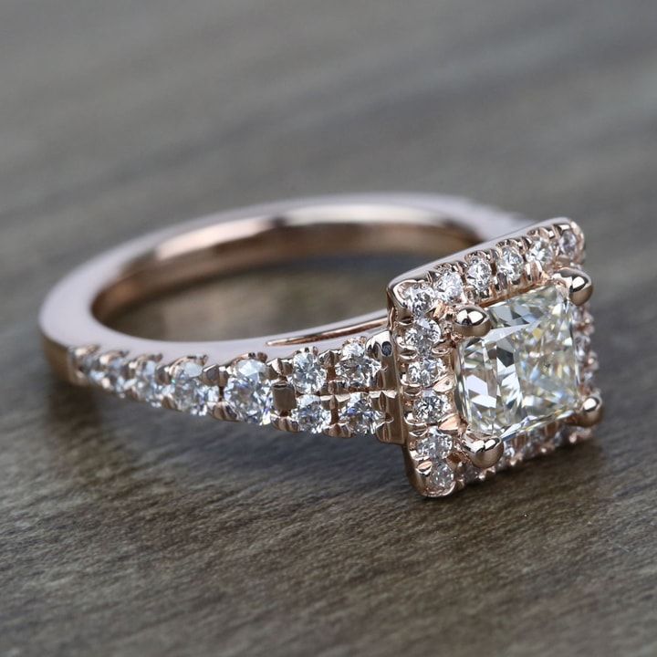 an engagement ring with a square cut diamond surrounded by smaller round diamonds