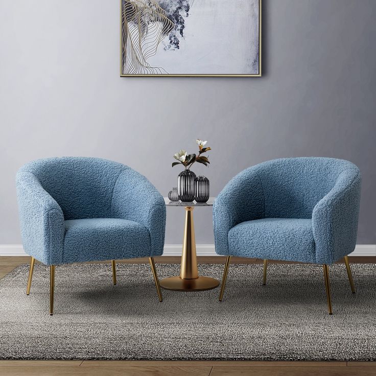 two blue chairs sitting next to each other on top of a rug