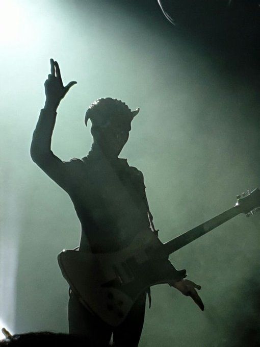 the silhouette of a man holding a guitar on stage