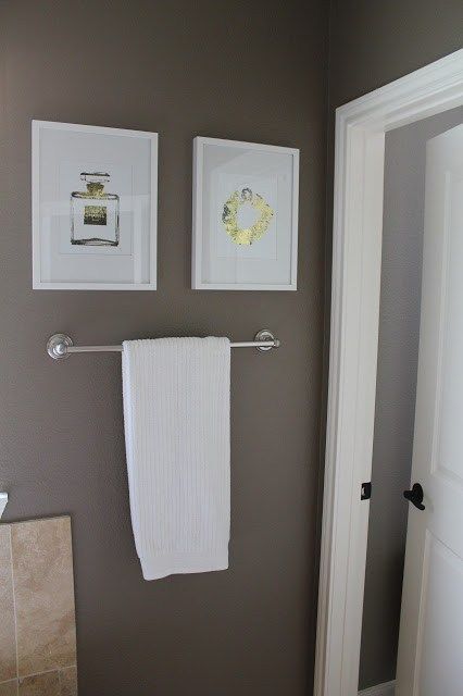 a bathroom with two pictures on the wall and a towel rack in front of it