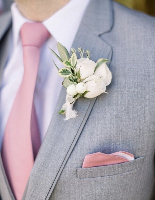 a man in a gray suit with a pink tie and flower boutonniere