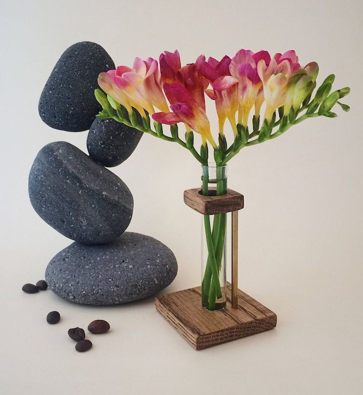 a vase filled with flowers sitting on top of a table next to rocks and pebbles