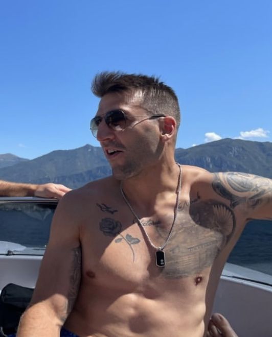 a shirtless man on a boat with mountains in the background