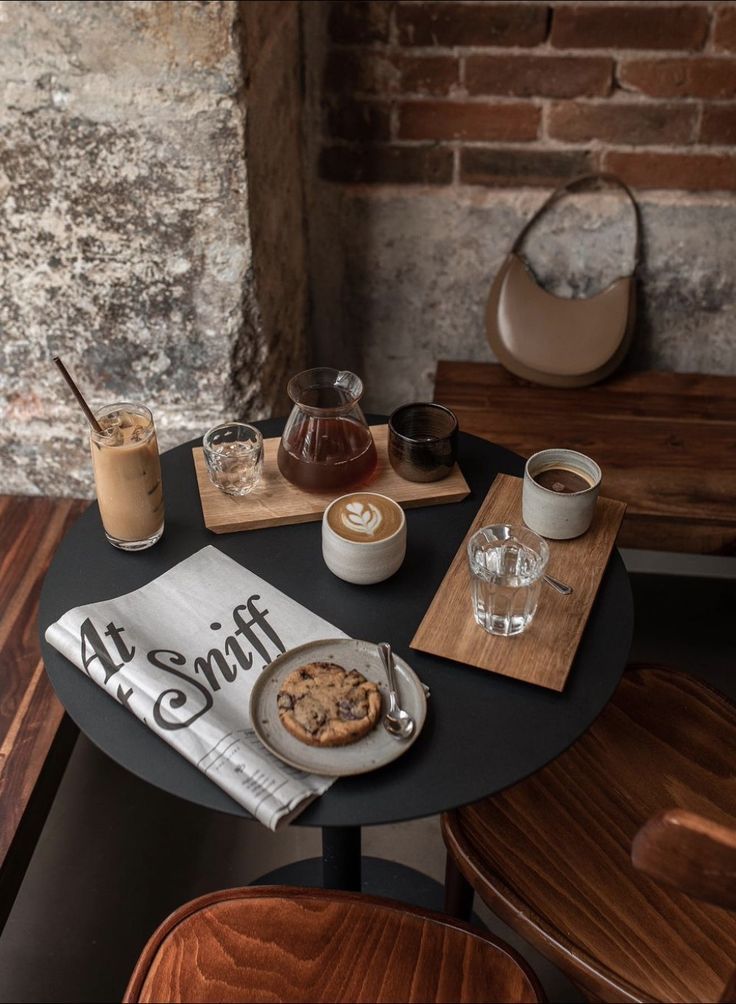 a table topped with plates and cups filled with desserts next to a brick wall