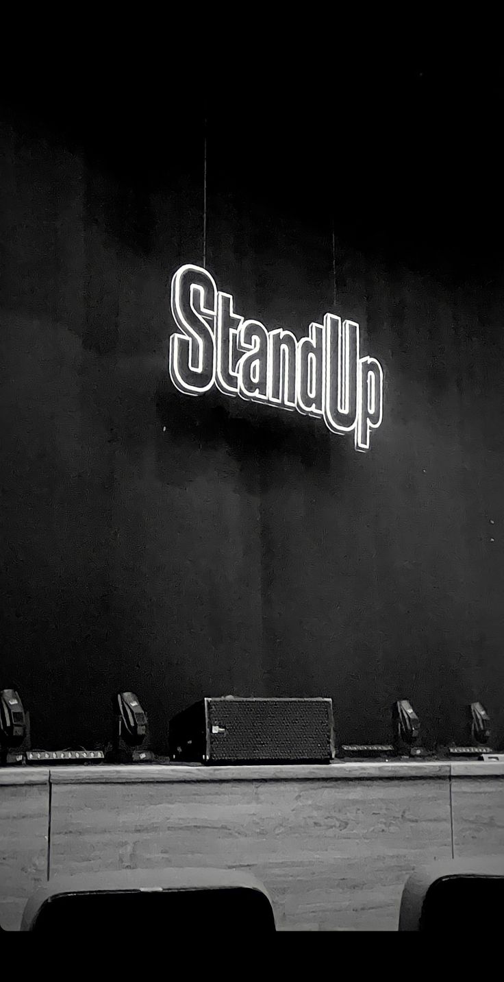 black and white photograph of stand up sign on the side of a building with chairs around it