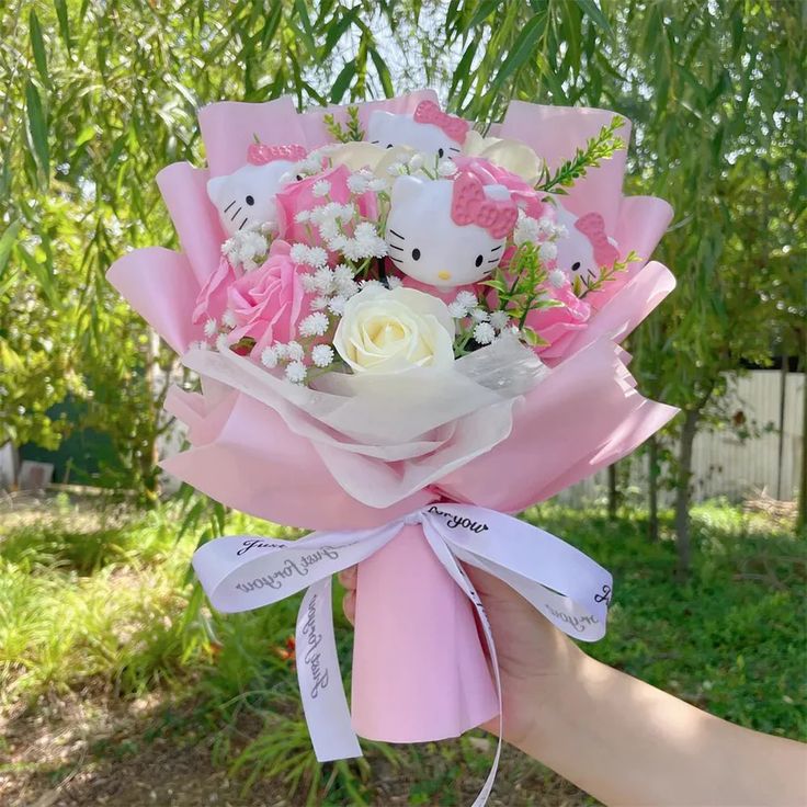 someone holding a pink and white bouquet with hello kitty on it