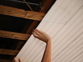 a woman reaching up to grab something off the ceiling