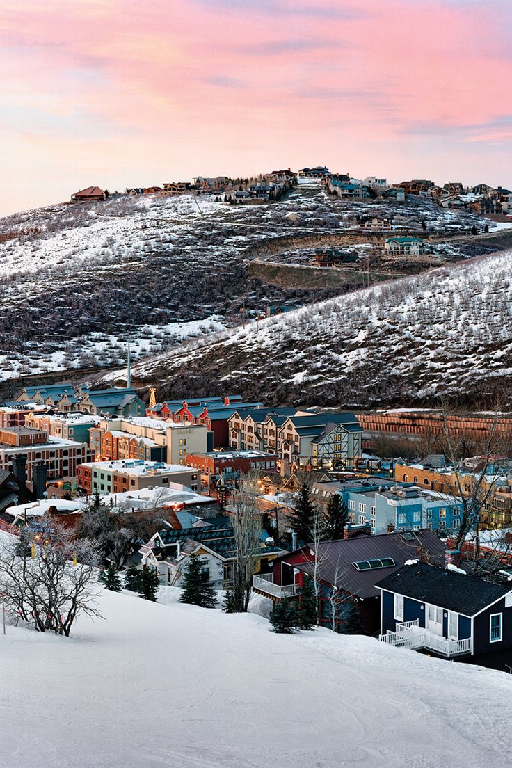 the town in winter with snow on the ground and mountains behind it - stock image