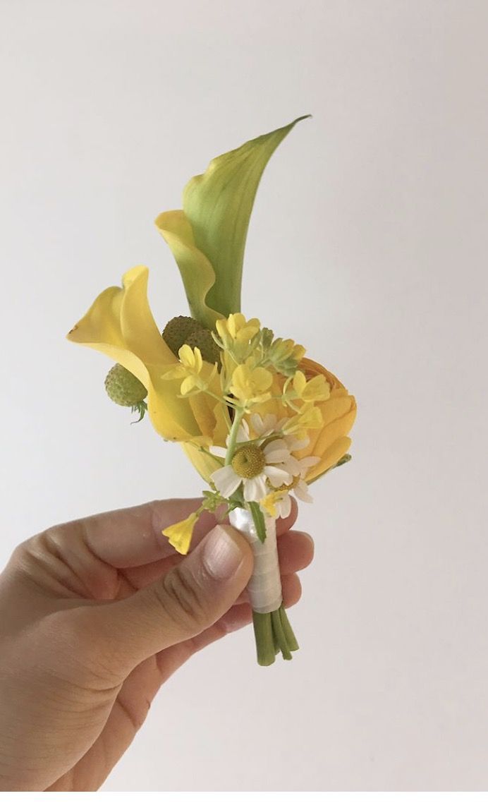 a person holding a yellow flower in their hand