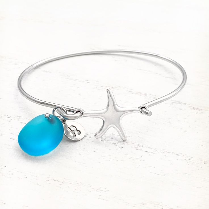 Playful yet refined, the Sea Glass Charm Bracelet is a lovely adornment that captures the essence of the wonders of the seas. Details: Stainless Steel Bangle: 67.5mm x 57mmCharm: Brass With Imitation Rhodium Plating, 19mmOcean Blue Sea Glass, 16.5mmOpen Front Design Fits All Sizes Adjustable Silver Bracelet With Ocean-inspired Style, Adjustable Silver Bracelets With Ocean-inspired Style, Adjustable Silver Ocean-inspired Bracelets, Silver Adjustable Ocean-inspired Bracelets, Ocean-inspired Starfish Bracelets As Gifts, Beach Glass Bracelet Jewelry, Beach Bangle Bracelets In Metal, Turquoise Ocean-inspired Bracelet With Lobster Clasp, Elegant Starfish Bracelets For Beach