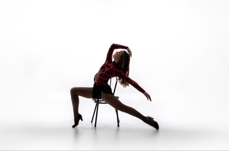 a woman sitting in a chair with her legs spread out and hands behind her head