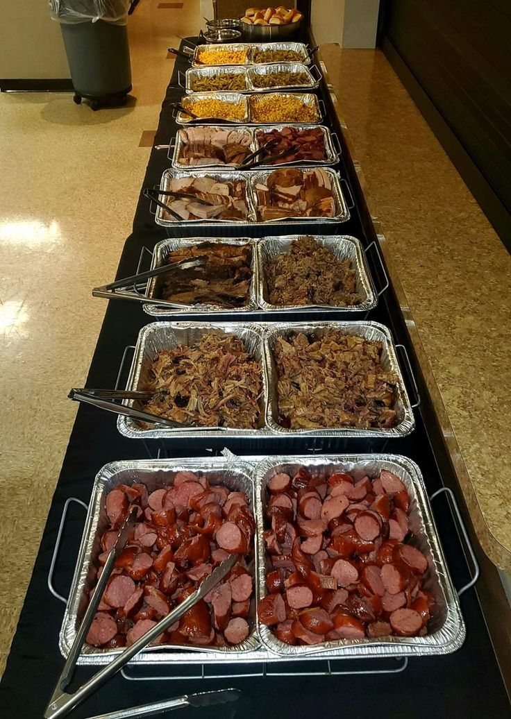 several trays of food are lined up on a long table