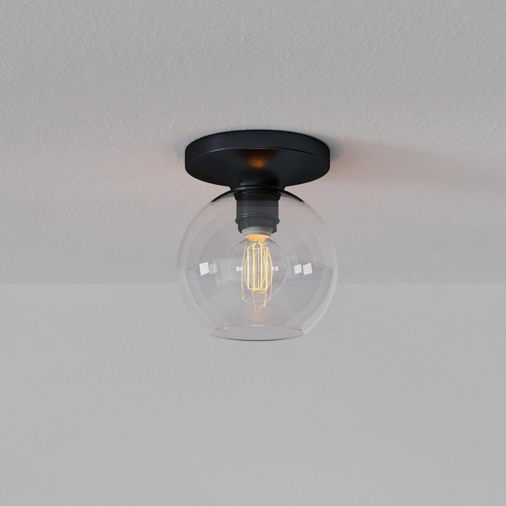 a light that is inside of a glass ball on the ceiling in a room with white walls