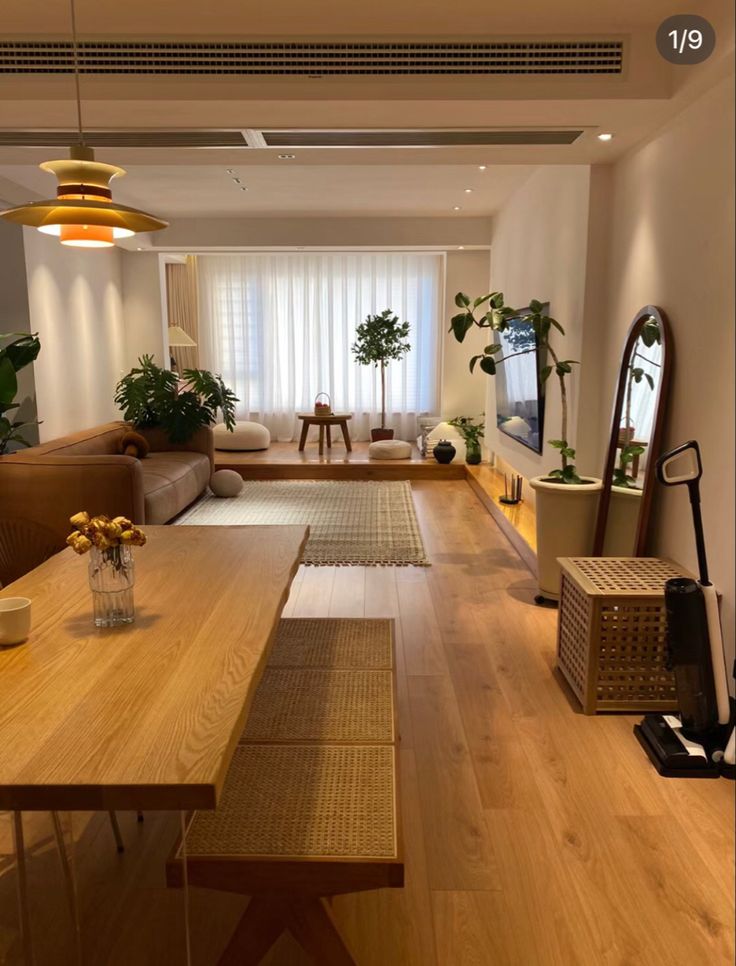 a living room filled with lots of furniture and plants on top of wooden flooring