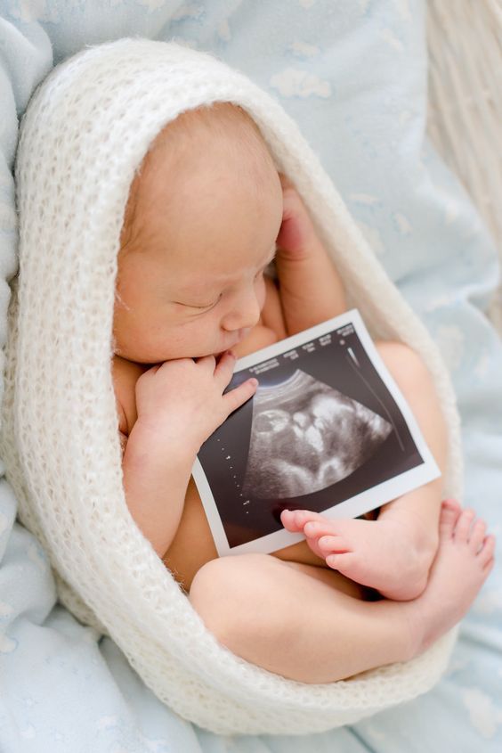 a baby wrapped in a blanket is holding an image of its mother's breast