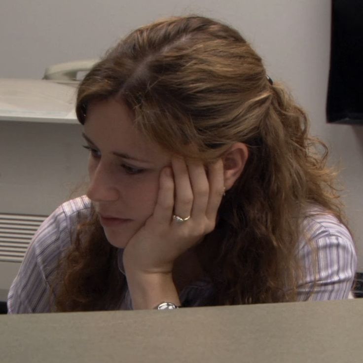 a woman sitting at a desk with her hand on her head