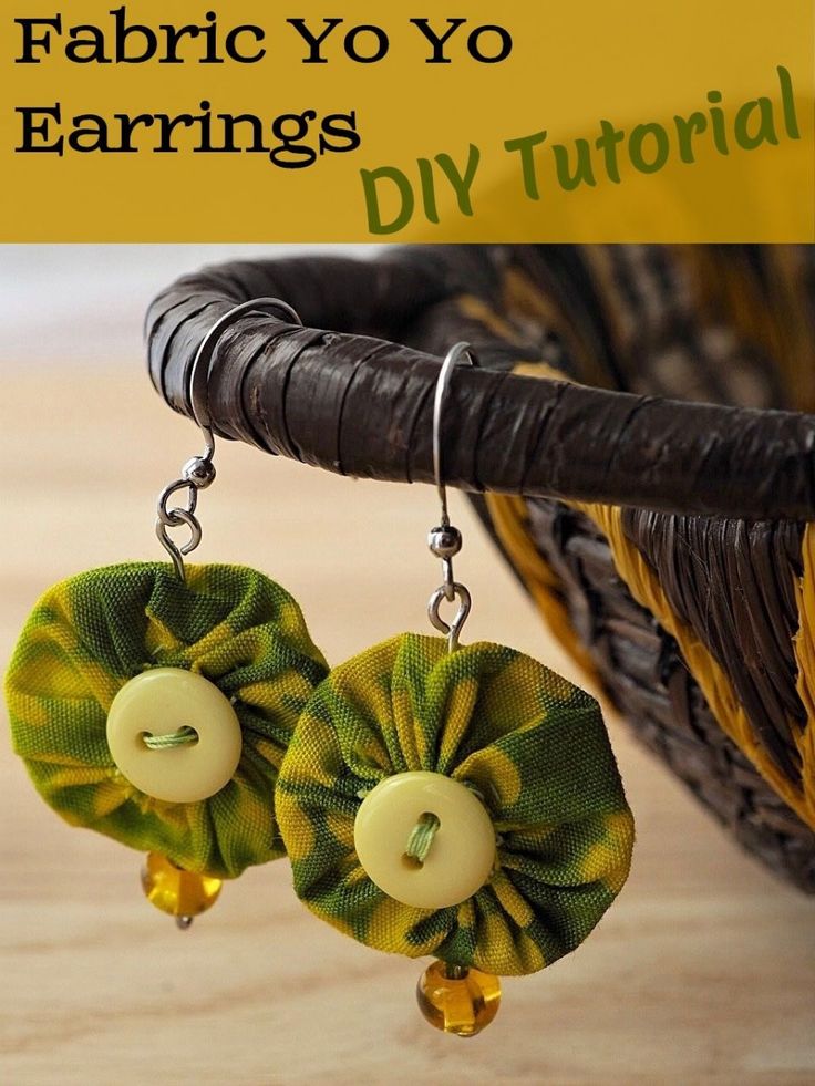 fabric yo yo earrings with yellow buttons and green flowers on them, hanging from a basket