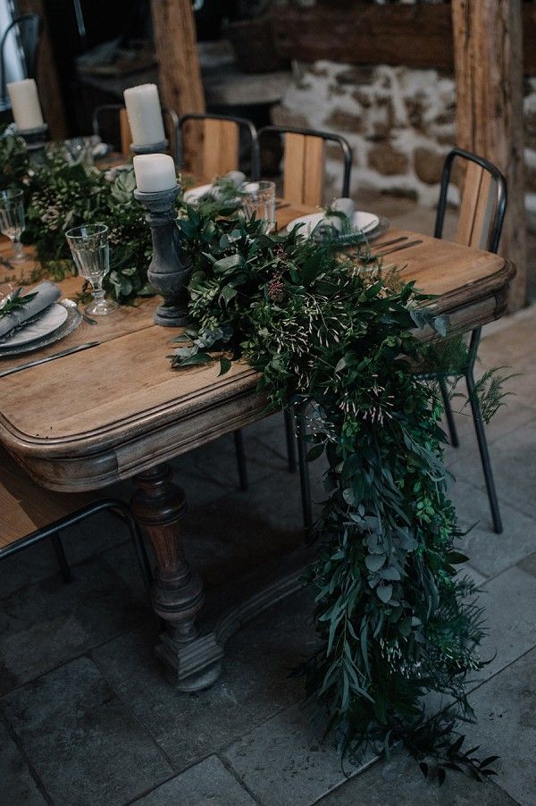 the table is set with greenery and candles