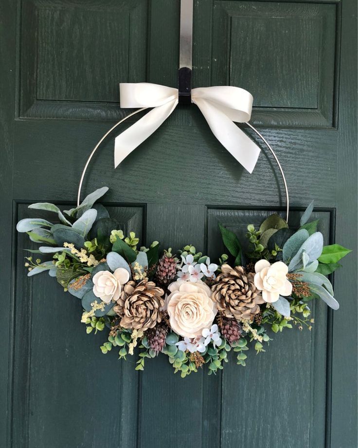 a wreath with flowers and pine cones hanging on a door