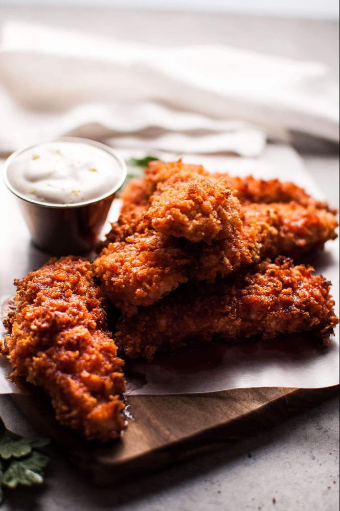 some fried food is on a wooden board with a small bowl of ranch dressing next to it