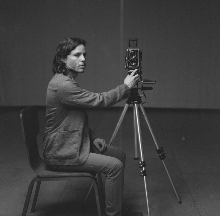 a man sitting in a chair with a camera on a tripod next to him