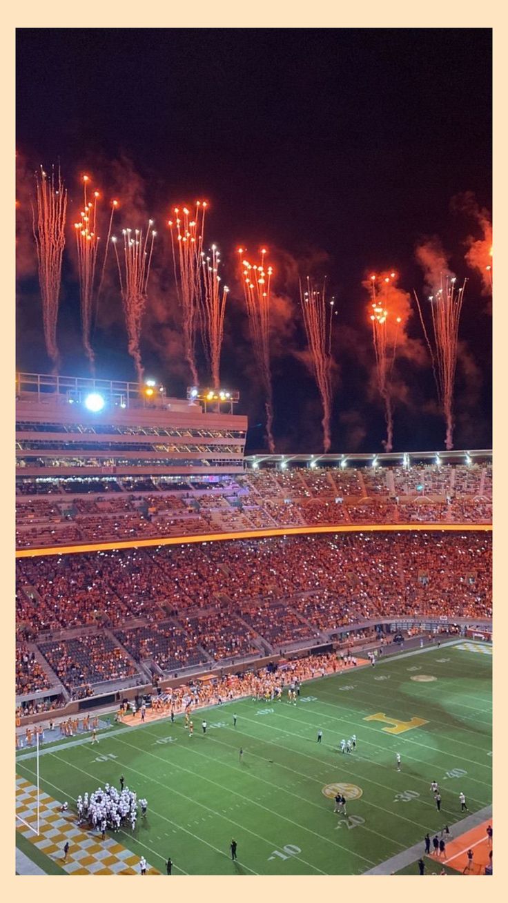 fireworks illuminate the night sky over an empty football stadium filled with spectators and fans