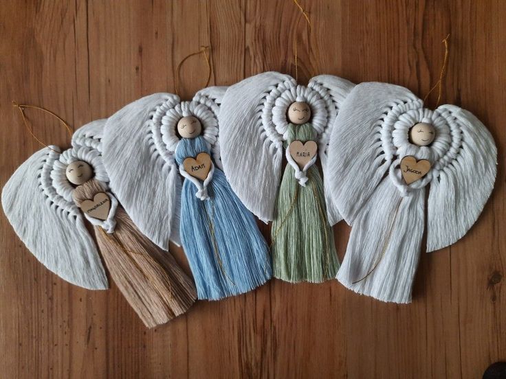 five angel ornaments are hanging on a wooden table